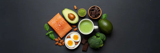 Matcha tea with keto-friendly foods like avocado, eggs, salmon, nuts, and greens on a dark background