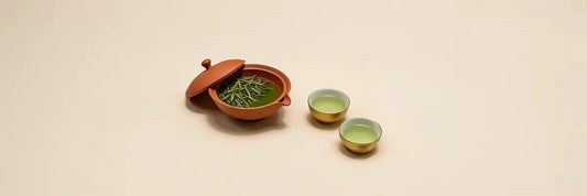 Traditional Japanese shiboridashi teapot with loose leaf green tea and two cups of brewed tea on minimalist background
