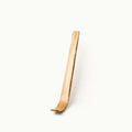 A single light natural wood object with a curved, tapered shape standing upright against a plain white background.
